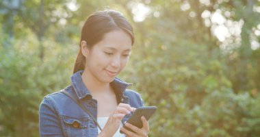 Kadın smartphone üzerinde yeşil arka plan üzerinde kontrol edin
