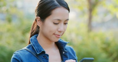 Kadın smartphone üzerinde yeşil arka plan üzerinde kontrol edin