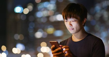 Geceleri cep telefonu kullanan adam.