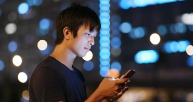 Adam cep telefonuyla şehirde geceleri