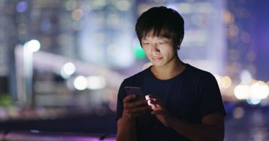 Genç adam cep telefonuyla şehirde geceleri