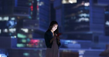 Kadın iş üstünde hareket eden telefon şehrin geceleri