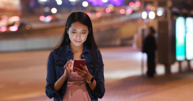 Geceleri cep telefonu kullanan bir kadın.