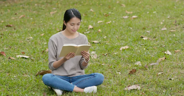 女は本を読んで緑の芝生に座って — ストック写真