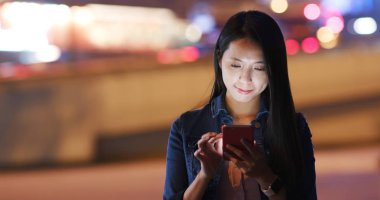 Kadına bak smartphone vasıl bokeh arka plan üzerinde geceleri