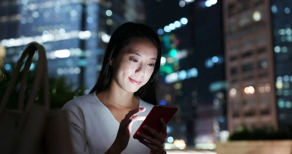 Woman work on smartphone in city at night