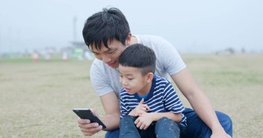 Cep telefonuyla oğluyla baba 