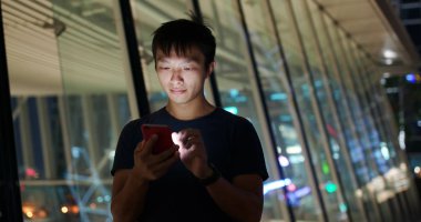 Geceleri cep telefonu kullanan adam.