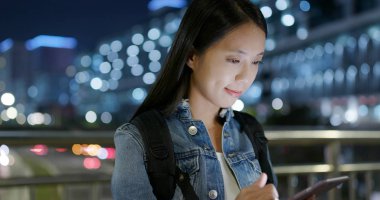 Gece şehirde akıllı telefon kullanan bir kadın.