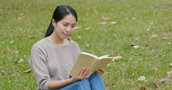 女は本を読んで緑の草の上に座って — ストック写真