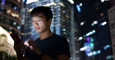 Geceleri cep telefonu kullanan adam.