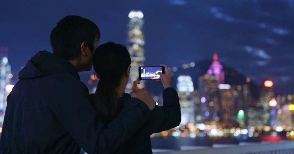 Couple using mobile phone for take photo in Hong Kong at night