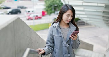 Şehirde akıllı telefon kullanan bir kadın