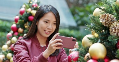 Kadın Noel ağacında fotoğraf çekiyor.