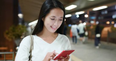 Kadın cep telefonuyla yaya köprüsünün geceleri