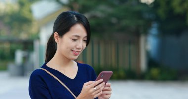 Parkta cep telefonu kullanan bir kadın.