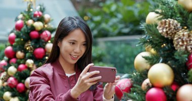 Kadın fotoğraf çalıştırırsam cellphone ile Noel ağacı süsle 