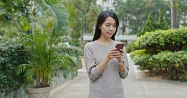 Kadın iş üstünde hareket eden telefon içinde şehir parkı