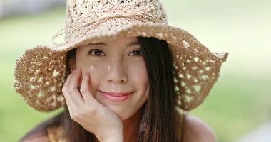 Yazın hasır şapkayla kameraya gülümseyen kadın