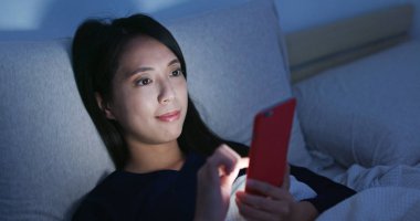 Cep telefonu kullaranarak ve yatakta yatıyordu kadın