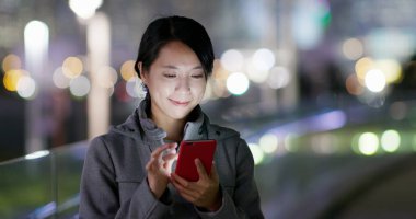 Geceleri cep telefonu kullanan bir kadın.