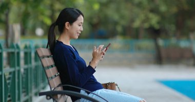 Parkta cep telefonu kullanan bir kadın.