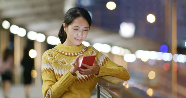 Woman using mobile phone in city at night