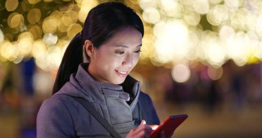 Woman using mobile phone over golden light blur background