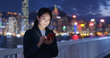 Geceleri cep telefonu kullanan bir kadın.