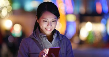 Woman using mobile phone over golden light blur background