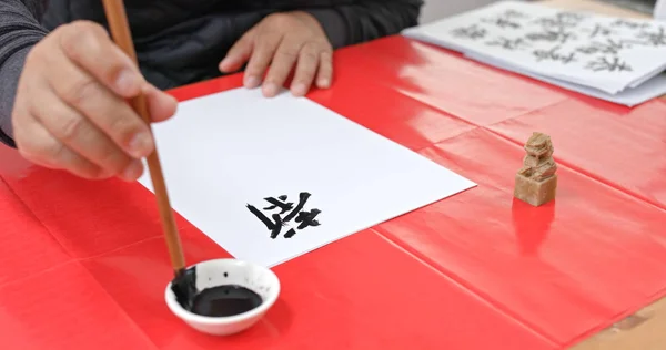 Man practice writing chinese calligraphy for lunar new year, words mean luck