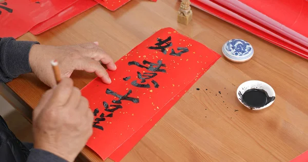 Old man writing Chinese calligraphy words means lucky and everything smooth in the new year
