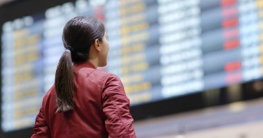 Woman look at the flight number display board in the airport