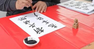 Man pratice chinese calligraphy for lunar new year, words mean wish you a prosperous Year clipart