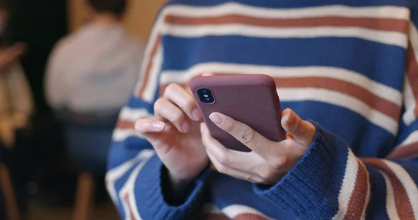Woman play game on cellphone inside coffee shop