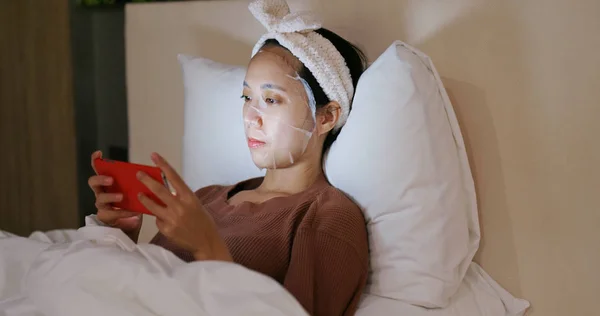 Wanita Mengenakan Masker Wajah Tempat Tidur Dan Menggunakan Ponsel Malam — Stok Foto