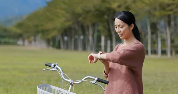 Woman using smart watch to check the location with her bike at countryside