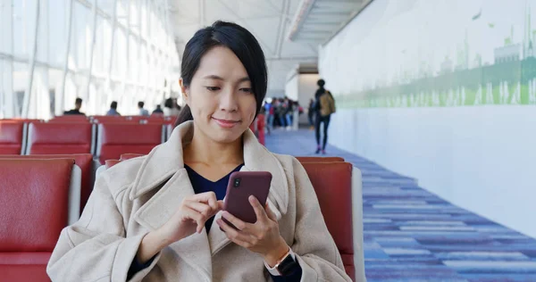 Woman uses mobile phone inside the check in area in the airport