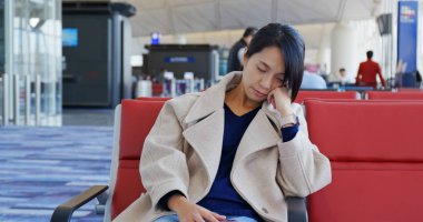 Kadın uyuyor ve havaalanındaki çeklerin üzerine oturuyor.