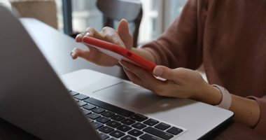 Kadın cep telefonu ve dizüstü bilgisayarla çalışıyor