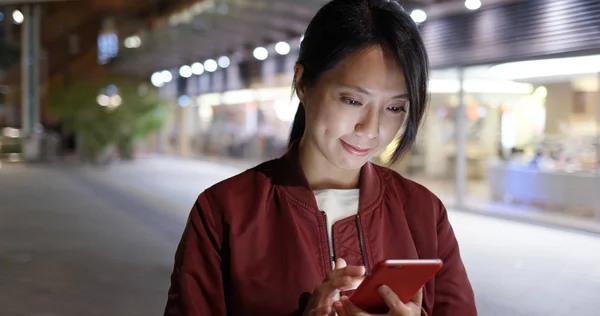 Woman check on smartphone in city at night