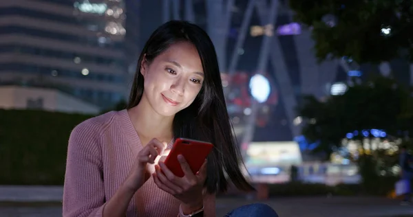 Woman check on mobile phone in city at night