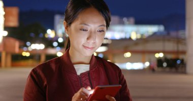 Geceleri Asyalı kadın cep telefonu kullanıyor.