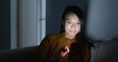 Kadın kullanın cep telefonu ve gece kanepede uzanmış