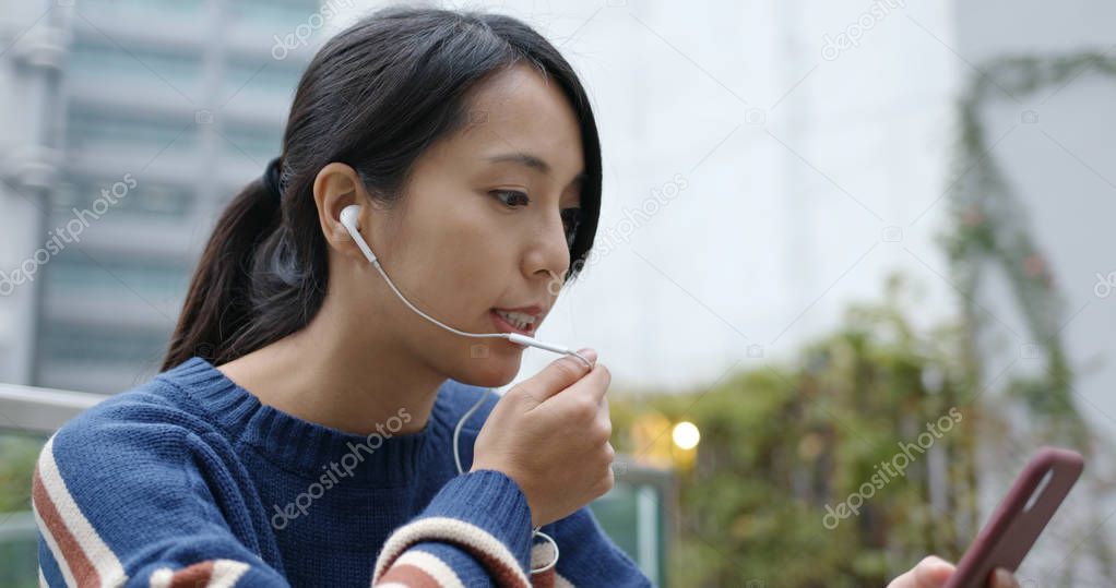 Woman having voice message on cellphone at city