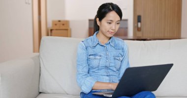 Bilgisayar üzerinde kadın çalışması ve evde kanepede oturmak