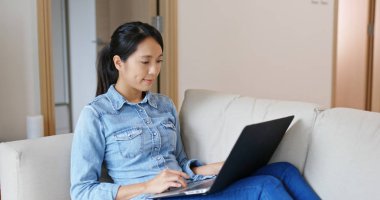 Bilgisayar üzerinde kadın çalışması ve evde kanepede oturmak