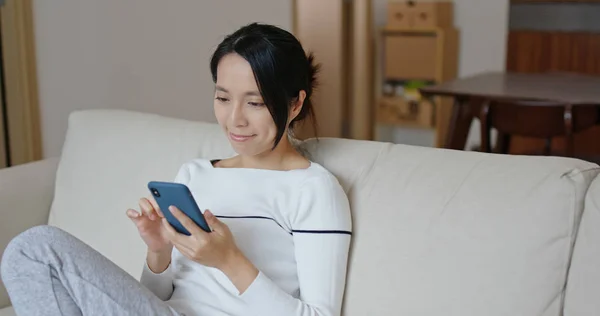 Frau Schaut Aufs Handy Und Sitzt Auf Sofa — Stockfoto