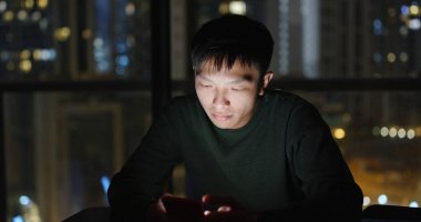 Geceleri cep telefonu kullanan bir adam.