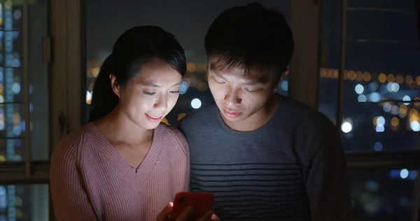 Asian couple look at mobile phone at night